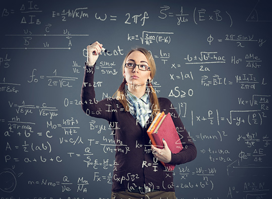 An image of a bespectacled young woman writing on a board covered in mathematical formulae.